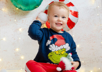 Ein kleiner Junge lacht in die Kamera und wirft im Fotostudio einen Schneeball