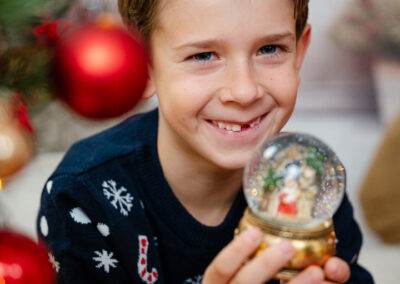 Ein Junge mit Zahnlücke lacht in die Kamera und hat einen weihnachtspulli an
