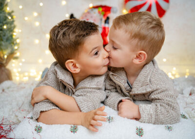 Ein Bruderfoto zu Weihnachten. Der kleine Bruder gibt dem großen Bruder einen Kuss auf die Wange