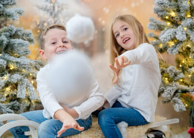 Zwei Kinder werfen künstliche Schneebälle zu einem Fotografen ins Bild