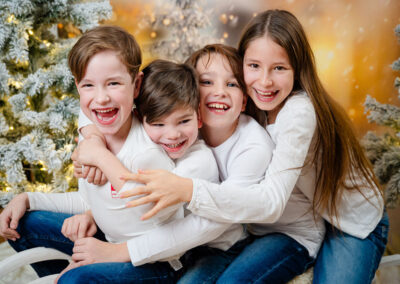 4 Kinder auf einem Schlitten mit weissen Oberteilen und Jeans