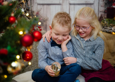 Ein Geschwisterpaar schaut in eine Glaskugel bei Weihnachtsbildern
