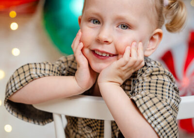 Weihnachtsfotos mit einem Mädchen. Sie lehnt sich auf die Armlehne eines Stuhls und hält ihren Kopf