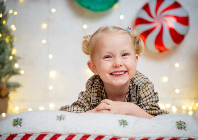 Ein Mädchen mit Zöpfen liegt auf dem Bauch und lacht. Im Hintergrund glitzernde Lichter